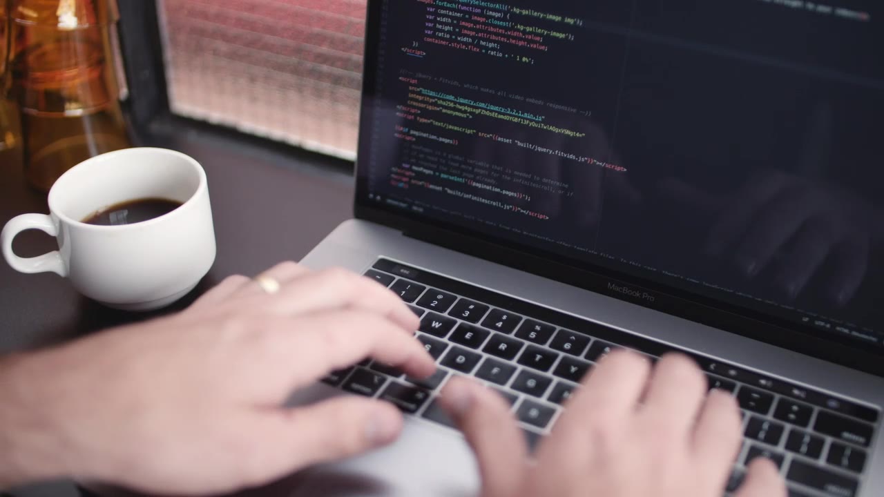 Hands working on code beside a coffee